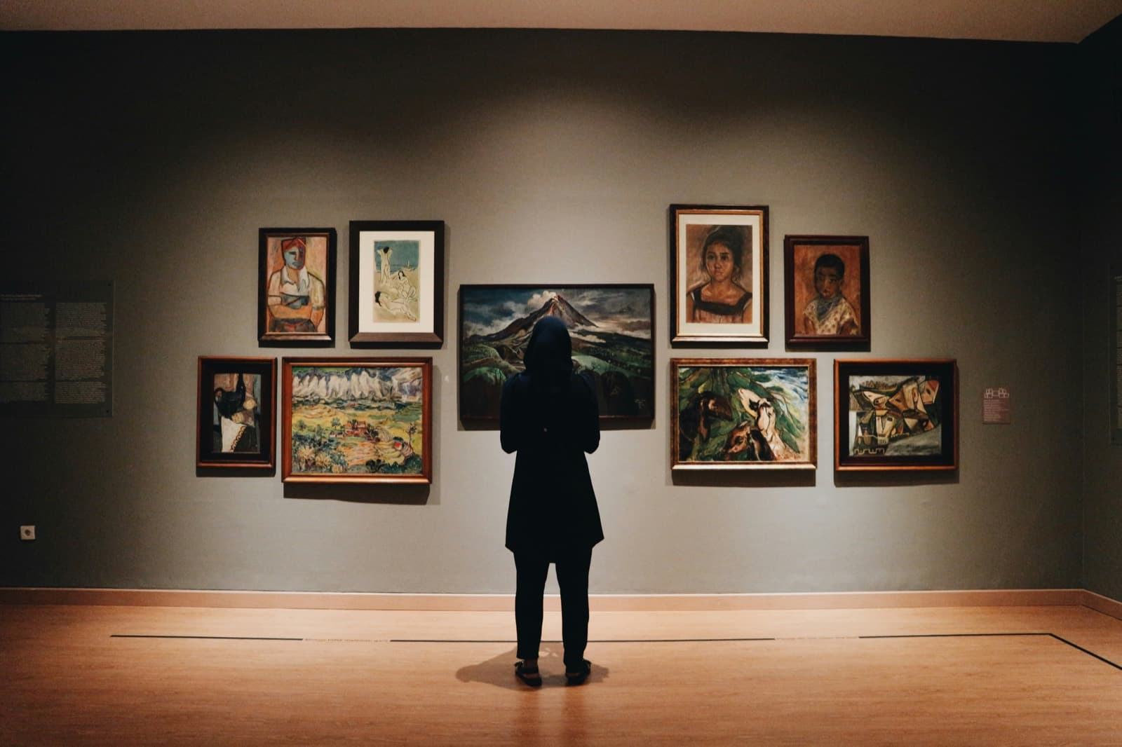 Visiteur devant un accrochage de tableaux encadrés